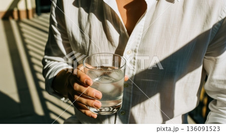 Person in White Shirt Holding a Cold Glass of Water with Ice Person in White Shirt Holding a Cold Glass of Water with Ice 136091523