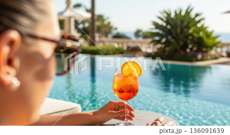 Vibrant Orange Spritz Cocktail on Poolside Table Under Clear Sky Vibrant Orange Spritz Cocktail on Poolside Table Under Clear Sky 136091639