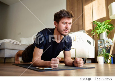 Man doing plank exercise on fitness mat at home 136092695