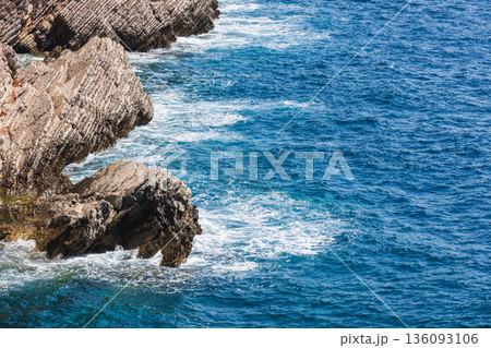 Rugged coastal rocks rise from the deep blue sea Rugged coastal rocks rise from the deep blue sea 136093106