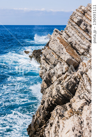 Rugged rocky cliffs meet the deep blue sea Rugged rocky cliffs meet the deep blue sea 136093111