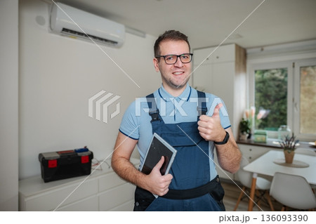 Repairman giving thumbs up after checking air conditioner Repairman giving thumbs up after checking air conditioner 136093390