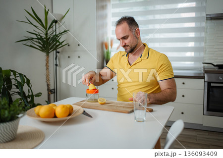 Man squeezing fresh lemon juice for healthy lifestyle drink Man squeezing fresh lemon juice for healthy lifestyle drink 136093409