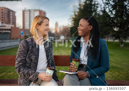 Diverse women colleagues enjoying coffee break in city park Diverse women colleagues enjoying coffee break in city park 136093507
