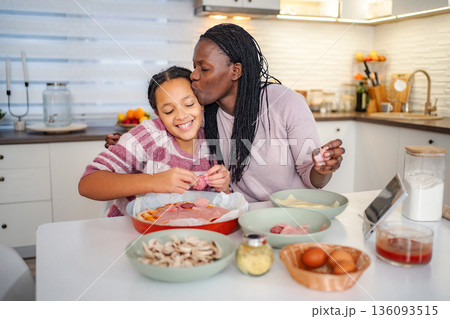 Mother and daughter making pizza bonding in kitchen 136093515