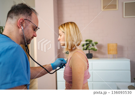 Doctor using stethoscope checking woman with rash at home Doctor using stethoscope checking woman with rash at home 136093530