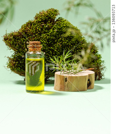 Glass bottle of essential juniper oil with wooden base and moss background on green. Copy space. Glass bottle of essential juniper oil with wooden base and moss background on green. Copy space. 136093713