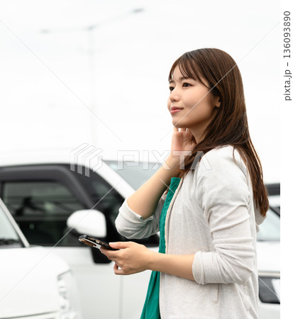 駐車場で携帯電話を持つ女性 ■撮影協力：関西国際空港（KIX） 136093890