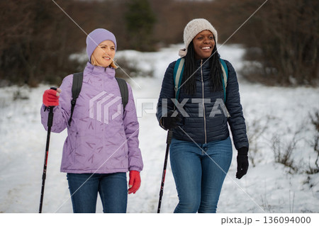 Women friends hiking on snowy winter mountain trail enjoying nature Women friends hiking on snowy winter mountain trail enjoying nature 136094000