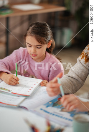 Little girl concentrating on homework learning with adult 136094004