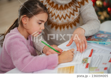 Mother helping daughter with homework at home Mother helping daughter with homework at home 136094005