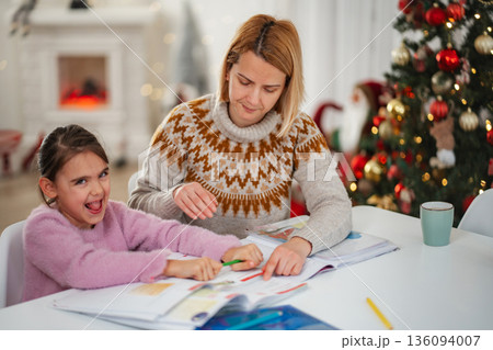 Mother helping daughter with homework at home during Christmas season Mother helping daughter with homework at home during Christmas season 136094007