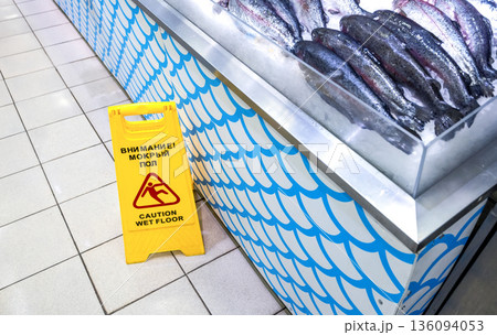 Caution Wet Floor warning sign on a floor at the fish department in a superstore 136094053