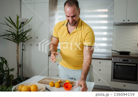 Man preparing fresh lemon juice for healthy morning routine Man preparing fresh lemon juice for healthy morning routine 136094159