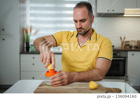 Man making fresh lemon juice in modern kitchen Man making fresh lemon juice in modern kitchen 136094160