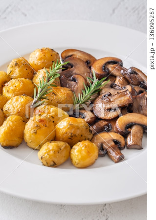Roasted baby potatoes with sauteed mushrooms and rosemary on minimalist white plate 136095287