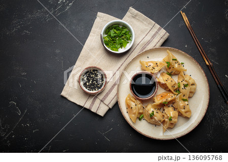 Gyoza dumplings soy sauce chopsticks asian Japanese food wontons black background 136095768