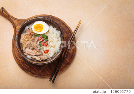 Asian soup rice noodles duck meat egg chopsticks ramen bowl light beige background copy space 136095770