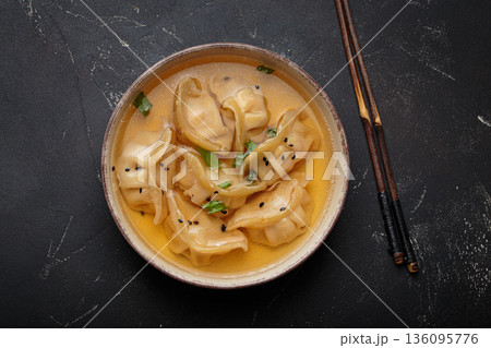 Gyoza dumplings broth soup chopsticks dark background bowl asian wontons Gyoza dumplings broth soup chopsticks dark background bowl asian wontons 136095776