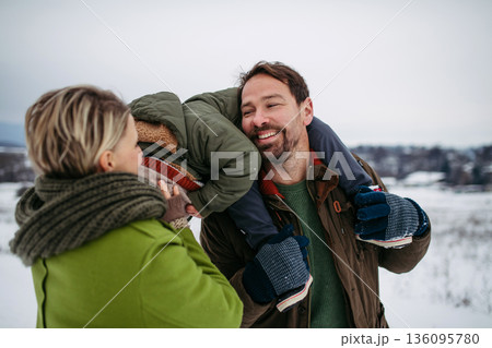 Parents and little son on walk in winter forest, during snowfall. Parents and little son on walk in winter forest, during snowfall. 136095780