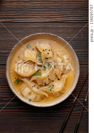 Gyoza dumplings broth soup chopsticks wooden background bowl asian wontons Gyoza dumplings broth soup chopsticks wooden background bowl asian wontons 136095787