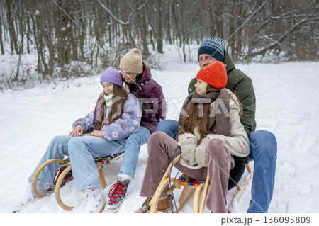 Family enjoying winter sledding together on snowy hill. Family enjoying winter sledding together on snowy hill. 136095809