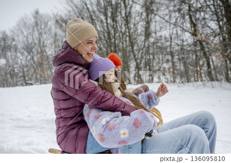 Family enjoying winter sledding together on snowy hill. Family enjoying winter sledding together on snowy hill. 136095810