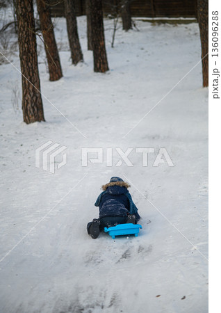 Little boy enjoying winter outdoor fun while sledding in snowy forest. Active childhood, seasonal outdoor recreation, winter adventure, family leisure and healthy lifestyle concept Little boy enjoying winter outdoor fun while sledding in snowy forest. Active childhood, seasonal outdoor recreation, winter adventure, family leisure and healthy lifestyle concept 136096288