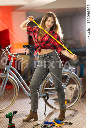 Young woman confidently holding measuring tape in workshop Young woman confidently holding measuring tape in workshop 136096468