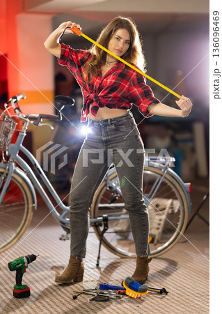 Woman holding measuring tape near bicycle workshop tools 136096469