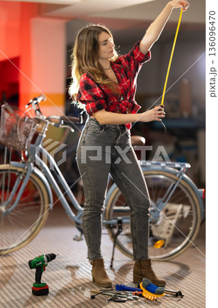 Woman measuring with tape working on bicycle maintenance Woman measuring with tape working on bicycle maintenance 136096470