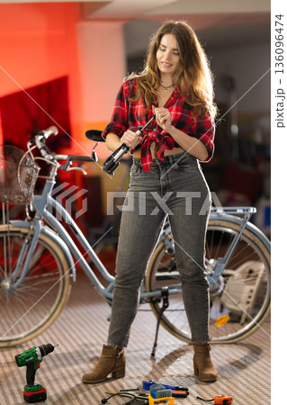 Young woman repairing bicycle, doing maintenance work 136096474