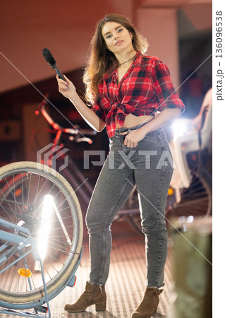 Young woman repairing bicycle wheel in workshop 136096538