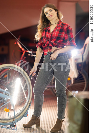 Young woman pumping bicycle tire feeling confident 136096539