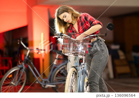 Young woman repairing urban bicycle with metal basket Young woman repairing urban bicycle with metal basket 136096564