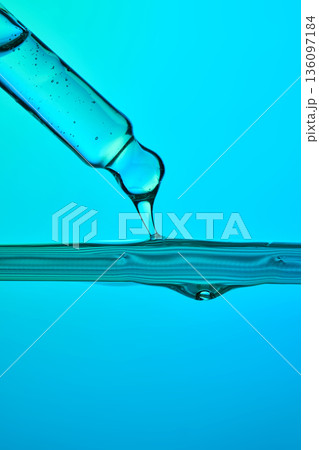 Dropper dispensing blue liquid into water surface Dropper dispensing blue liquid into water surface 136097184