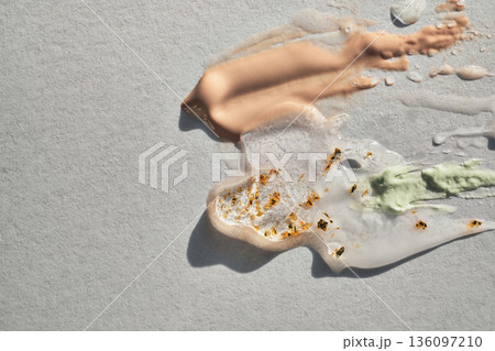 Different cosmetic products with gold flakes swatched on textured surface Different cosmetic products with gold flakes swatched on textured surface 136097210