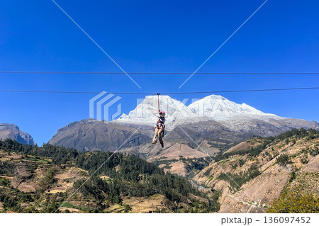 Teenage girl is doing canopy in front of the Huascaran, completely covered in snow. Ancash. Teenage girl is doing canopy in front of the Huascaran, completely covered in snow. Ancash. 136097452