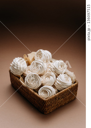 White meringue rosettes in wicker basket on beige background, copy space White meringue rosettes in wicker basket on beige background, copy space 136097515