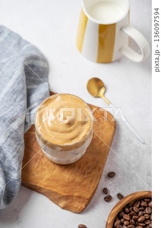 Iced Dalgona coffee on a wooden board on a gray concrete background with milk jug Iced Dalgona coffee on a wooden board on a gray concrete background with milk jug 136097594