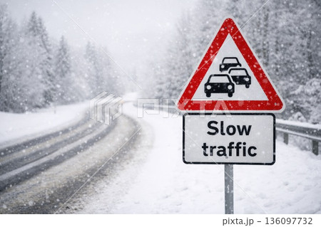 Slow Traffic Warning Road Sign During Heavy Winter Snowfall 136097732