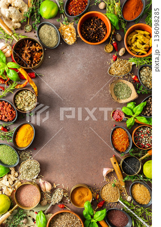 A colorful assortment of fragrant herbs and spices on a warm brown background, showcasing their visual variety and aromatic appeal, spice frame 136098285