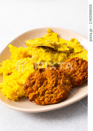 Colorful bowl of rice with rhubarb fried eggs, baked sweet potato, cauliflower, zucchini, and meat fritters alongside a fresh salad. Enjoy a nutritious and flavorful meal 136098608