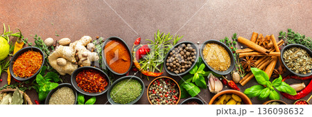 A rich palette of colorful spices and herbs, resting on a brown background, radiating freshness and an inviting aroma, perfect for gourmet inspiration, banner A rich palette of colorful spices and herbs, resting on a brown background, radiating freshness and an inviting aroma, perfect for gourmet inspiration, banner 136098632