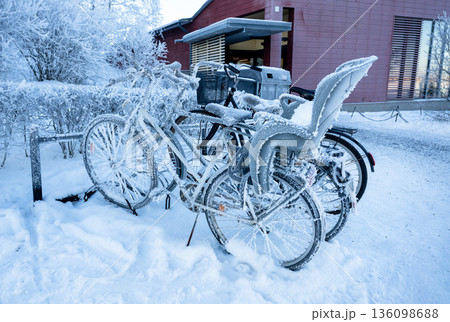 Snow covered bicycles parked on street in winter city of Finland in cold morning Snow covered bicycles parked on street in winter city of Finland in cold morning 136098688
