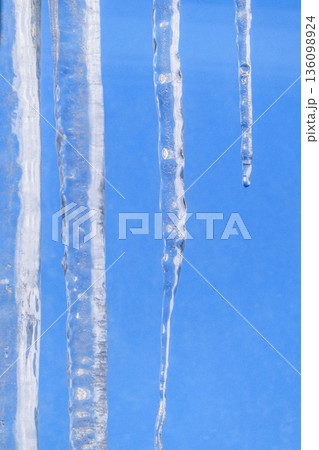 岩手県盛岡市の屋根からのびるつらら　冬の青空と溶け出したつらら　春近し 136098924