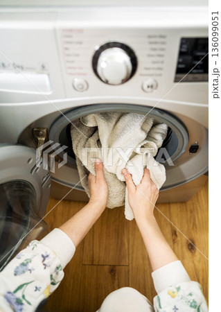 Washing machine at home. Smart appliances. Woman loading the washing machine with towels. Daily chores. Cleaning laundry 136099051