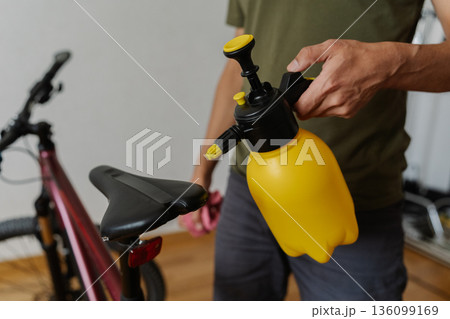 Close-up of bicycle mechanic spraying water on bicycle saddle performing detailed maintenance and cleaning in workshop environment, ensuring optimal hygiene and care. Concept of bike service. 136099169