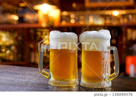 mugs of beer in a bar on wooden counter 136099376