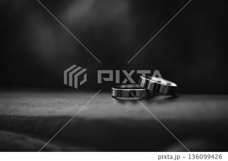 Two metal wedding rings on dark fabric surface with black background 136099426